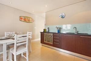 a kitchen with a table and a sink and a counter at Eden on The Bay 125 by HostAgents in Bloubergstrand