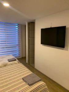 - une chambre avec un lit et une télévision murale à écran plat dans l'établissement Alojamiento tipo LOFT completo en barrio Las Aguas, à Bogotá