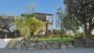 a house with a stone retaining wall and trees at Sunset Haven in Nelson in Nelson