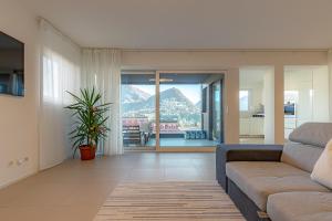 een woonkamer met een bank en uitzicht op een berg bij IMPERIAL of LUGANO apartment-behind the station with FREE parking in Lugano
