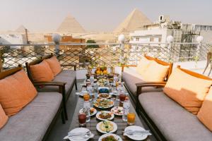a table with plates of food on a balcony with pyramids at Sphinx golden gate pyramids view in Cairo