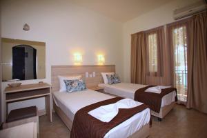 a hotel room with two beds and a mirror at Aktaion Guest Rooms in Skopelos Town