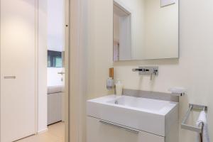 La salle de bains est pourvue d'un lavabo blanc et d'un miroir. dans l'établissement IMPERIAL of LUGANO apartment-behind the station with FREE parking, à Lugano