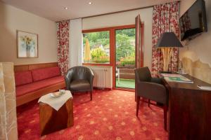ein Wohnzimmer mit einem Sofa, einem Tisch und Stühlen in der Unterkunft Flair Hotel Sonnenhof in Baiersbronn