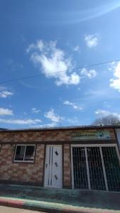 un edificio de ladrillo con dos puertas blancas y un cielo en Hostal La Casa De Mamá, en Arboletes