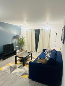 a living room with a blue couch and a table at Hemel Apartments- City Zen in Hemel Hempstead