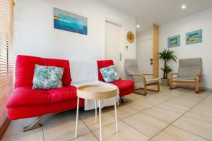 a living room with a red couch and a table at Hauzify I Apartament Llevant in Santa Susanna
