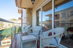un porche con sillas de mimbre y una mesa en el balcón en Hauzify I Apartament Llevant en Santa Susanna
