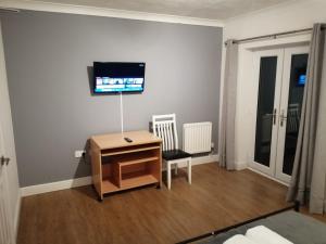 ein Wohnzimmer mit einem Schreibtisch und einem TV an der Wand in der Unterkunft Eagle Way Apartment in Peterborough