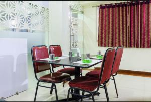 une salle à manger avec une table et des chaises rouges dans l'établissement Menaka, à Vijayawada