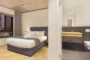 een slaapkamer met een bed en een badkamer met een wastafel bij Bridgewater View 415 by HostAgents in Kaapstad
