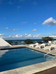 uma piscina com espreguiçadeiras e o oceano em Apart-Hotel em Tambaú - Super Central com Vista Mar - Ap.113 em João Pessoa