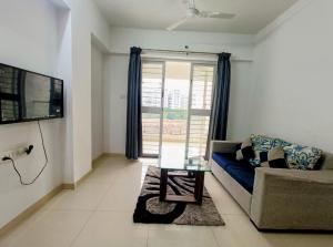 uma sala de estar com um sofá azul e uma mesa de vidro em Ornate Service Apartments em Pune