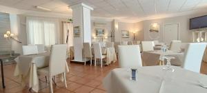 a dining room with white tables and white chairs at Hotel Palladium in Monastir