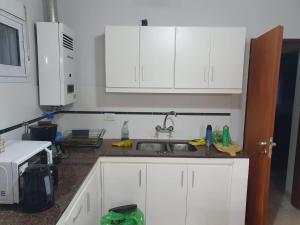 una cocina con armarios blancos y fregadero en Río Corrientes House en Monte Hermoso