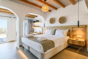 een slaapkamer met een groot bed met witte lakens bij Mykonos Residence Villas & Suites Merchia Beach in Merchia Beach