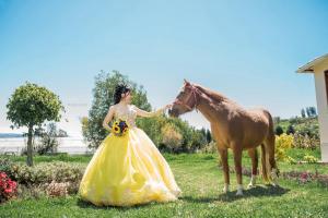 a woman in a yellow dress standing next to a horse at HOSTERÍA QUINTA INÉS MARÍA in Chambo
