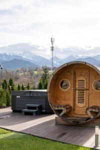 a large wooden pod sitting on a deck with mountains in the background at Osada LUX-HOUSE & SAUNA in Zakopane
