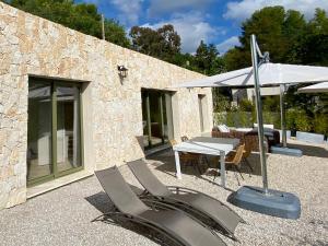 eine Terrasse mit 2 Stühlen, einem Tisch und einem Sonnenschirm in der Unterkunft Villa Jacuzzi Calme & Elegance - Prox Mer - Clim & Cheminée - Parking in Cagnes-sur-Mer