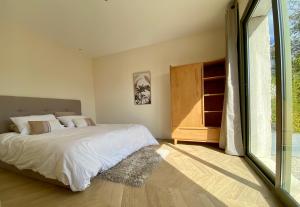 ein Schlafzimmer mit einem Bett und einem großen Fenster in der Unterkunft Villa Jacuzzi Calme & Elegance - Prox Mer - Clim & Cheminée - Parking in Cagnes-sur-Mer