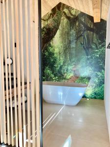 ein Badezimmer mit einer Badewanne in einem Waldbild in der Unterkunft Alpen Luxury Lodge, MARIAZELL in Mariazell