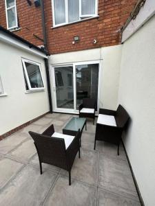 a patio with three chairs and a glass table at 3 Bed Home - Sleeps up to 5 - Coventry - Contractors, Families and Relocators in Coventry
