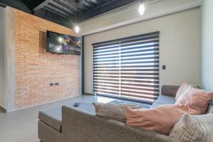 een woonkamer met een bank en een bakstenen muur bij Depa Industrial Moderno y Comodo in Durango