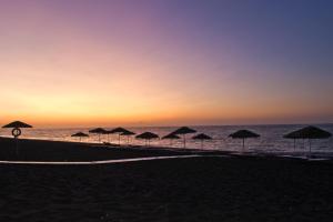 a group of umbrellas on the beach at sunset at Atlantis Beach Villa in Perivolos