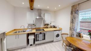 a kitchen with white cabinets and a sink and a table at Ludlow Escapes - Ludlow Town Centre Apartments in Ludlow