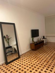 uma sala de estar com um espelho e uma televisão de ecrã plano em apartamento reformado e bem localizado no Humaitá no Rio de Janeiro