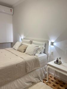 um quarto branco com uma cama branca e uma mesa em apartamento reformado e bem localizado no Humaitá no Rio de Janeiro