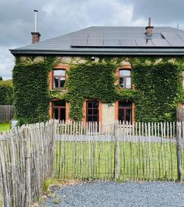 een huis bedekt met groene klimop achter een hek bij l'oiseau bleu in Rochehaut