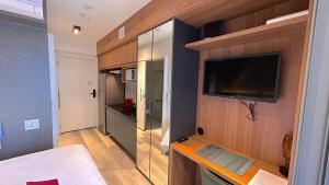 Il comprend un petit salon avec une télévision et une cuisine. dans l'établissement Zainalofts7 Moema - 1km Ibira e 200m metrô 811 ID, à São Paulo