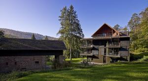 Restaurant Hôtel L'Arnsbourg في Baerenthal: عمارة سكنية كبيرة مع شرفة ومنزل