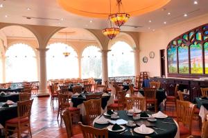 a dining room with tables and chairs and windows at Real Hacienda Santo Tomás in El Hospital