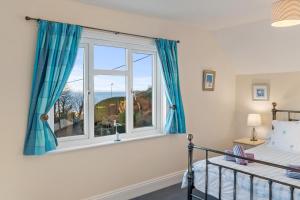 a bedroom with a bed and a window with blue curtains at Four Oaks - Sea and Harbour Views in Saundersfoot