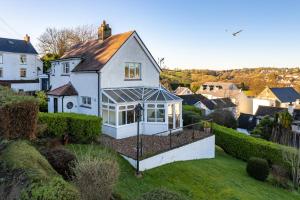 a white house with a conservatory on top of a yard at Four Oaks - Sea and Harbour Views in Saundersfoot