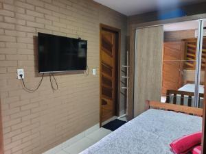 a bedroom with a flat screen tv on a brick wall at Rancho Santa Helena in Juazeiro