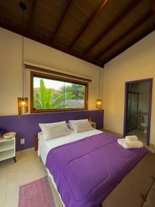 a bedroom with a large purple bed with a window at Tronco do Ipê Hospedagem in Alto Paraíso de Goiás