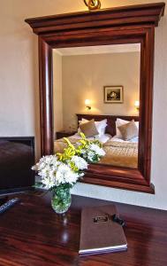 a bedroom with a large mirror and a table with flowers at Hotel Doupiani House in Kalabaka