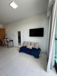 sala de estar con TV de pantalla plana en la pared en Flat Sol do Makia - Studio com vista para piscina, en Ipojuca