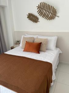 een slaapkamer met een bed met witte lakens en kussens bij Flat Sol do Makia - Studio com vista para piscina in Ipojuca