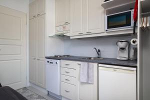 Una cocina con gabinetes blancos y un fregadero. en Pikkuriikkinen yksiö kaikilla herkuilla Levin keskustassa, en Levi