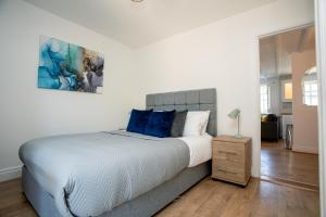 a bedroom with a large bed with blue pillows at Apartment in the heart of Old Town Beaconsfield in Buckinghamshire