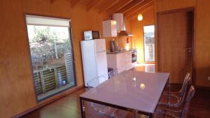 a kitchen with a table and a white refrigerator at Bungalow Sobre Águas Camping in Bragança