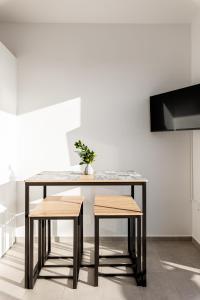 een tafel met twee krukken en een vaas met een plant bij Pagani Green - Luxury Studio A1 in Kalamata