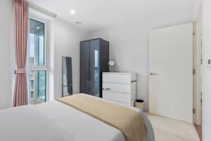 a white bedroom with a bed and a dresser at Lake View Hackney Two Bed in London