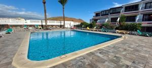 a swimming pool with blue water in front of a building at SEA VIEW in Silent Residence South TENERIFE in Costa Del Silencio