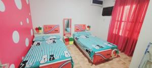 2 camas individuales en una habitación con cortinas rojas en 36ميلسا en El Cairo