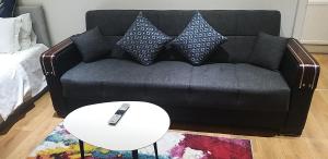 Sofá negro con almohadas y mesa blanca en Simply Relax,1 Eastham London, en Londres
